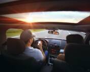 summer driving safety practices - man driving in car using phone looking out front windshield